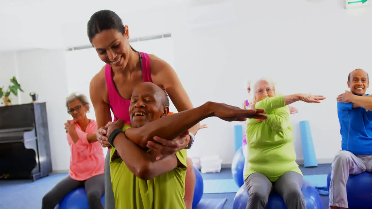 Front view of Caucasian female trainer training senior man in exercise at fitness studio 4k