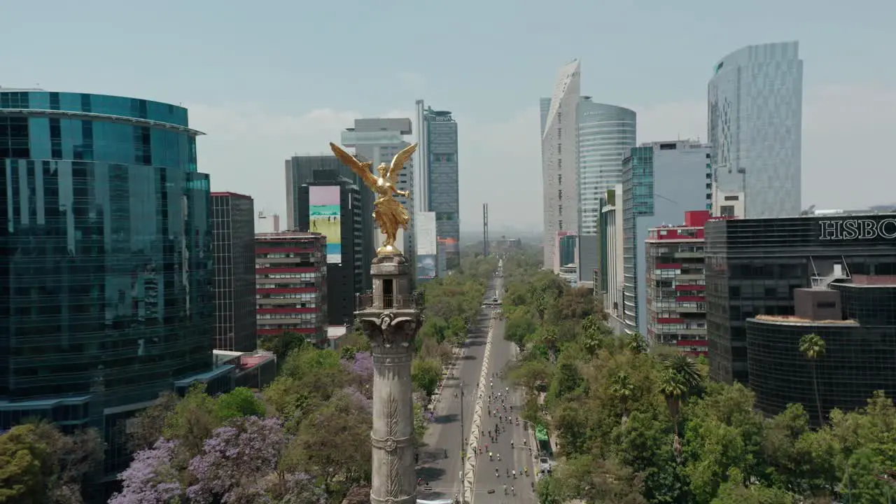 Aerial of monumento a la independencia landmark in mexico cyclists in background