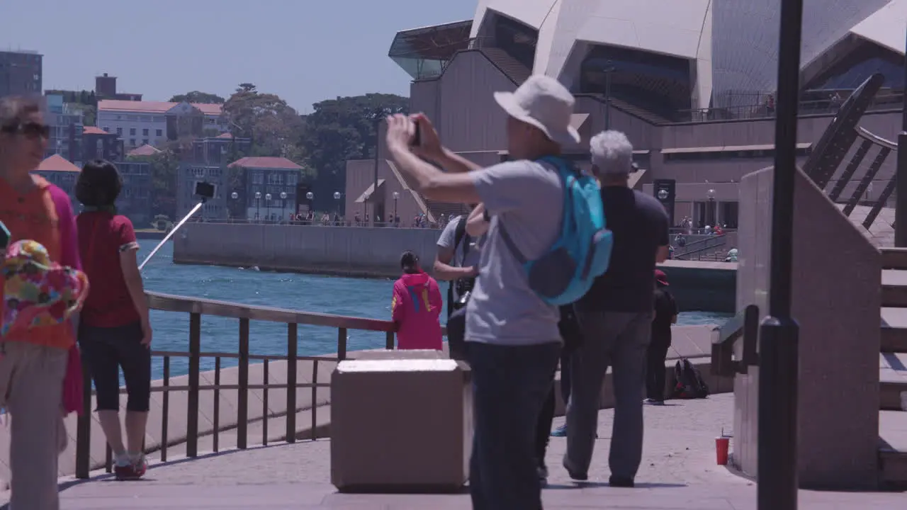 Many people on vacation in Australia take photos are the waterfront near the Sydney Harbor bridge