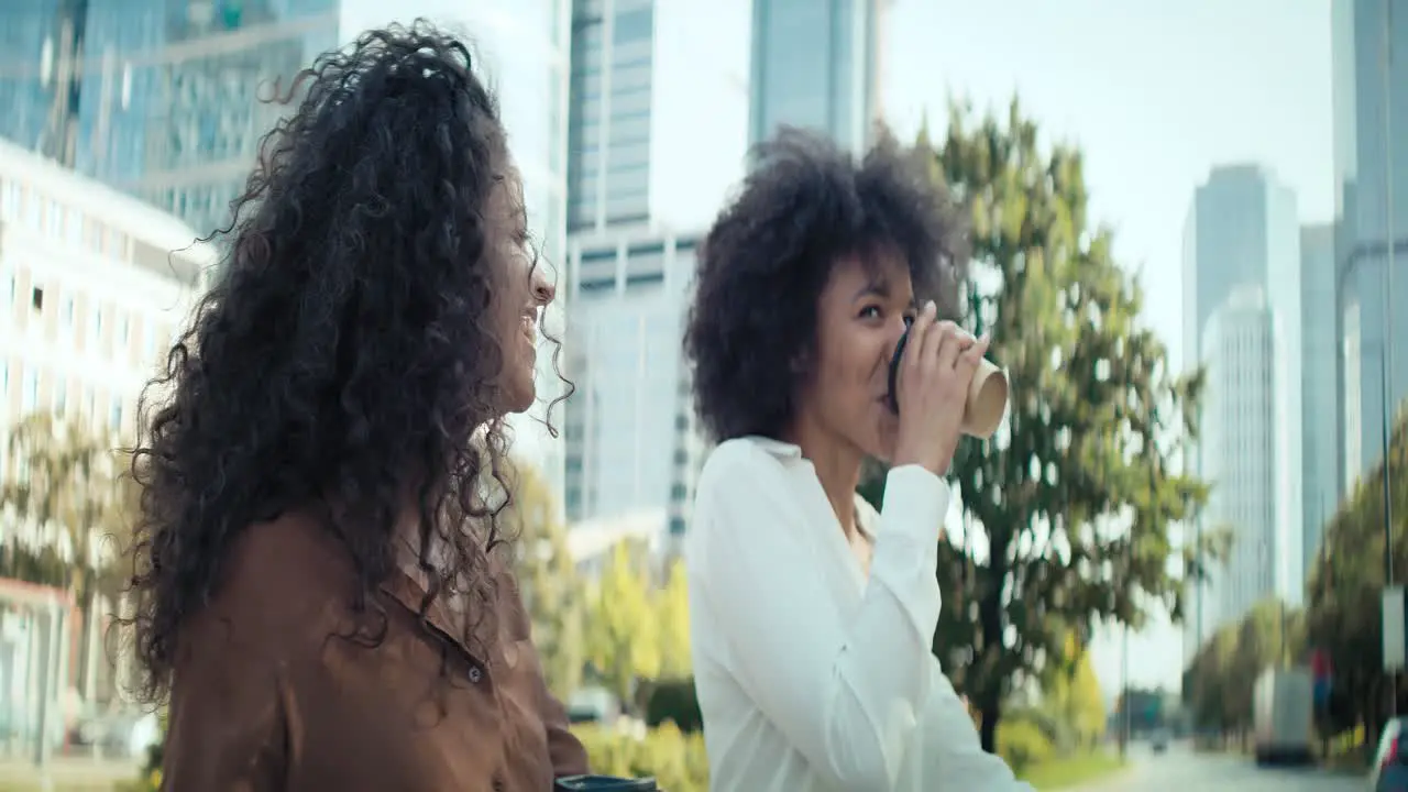 Video of two happy businesswomen walking with a mug of coffee