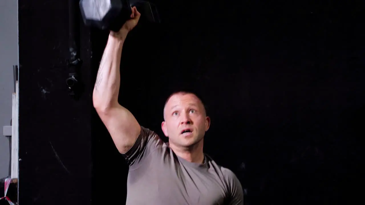 Big caucasian fitness athlete male lifting a heavy dumbbell of the ground in the air