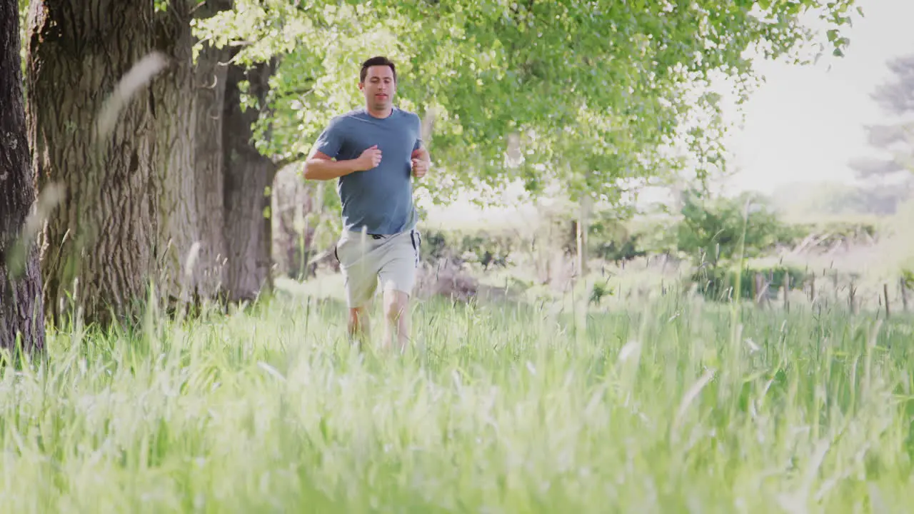 Crane Shot Of Man Exercising Running Through Countryside Field