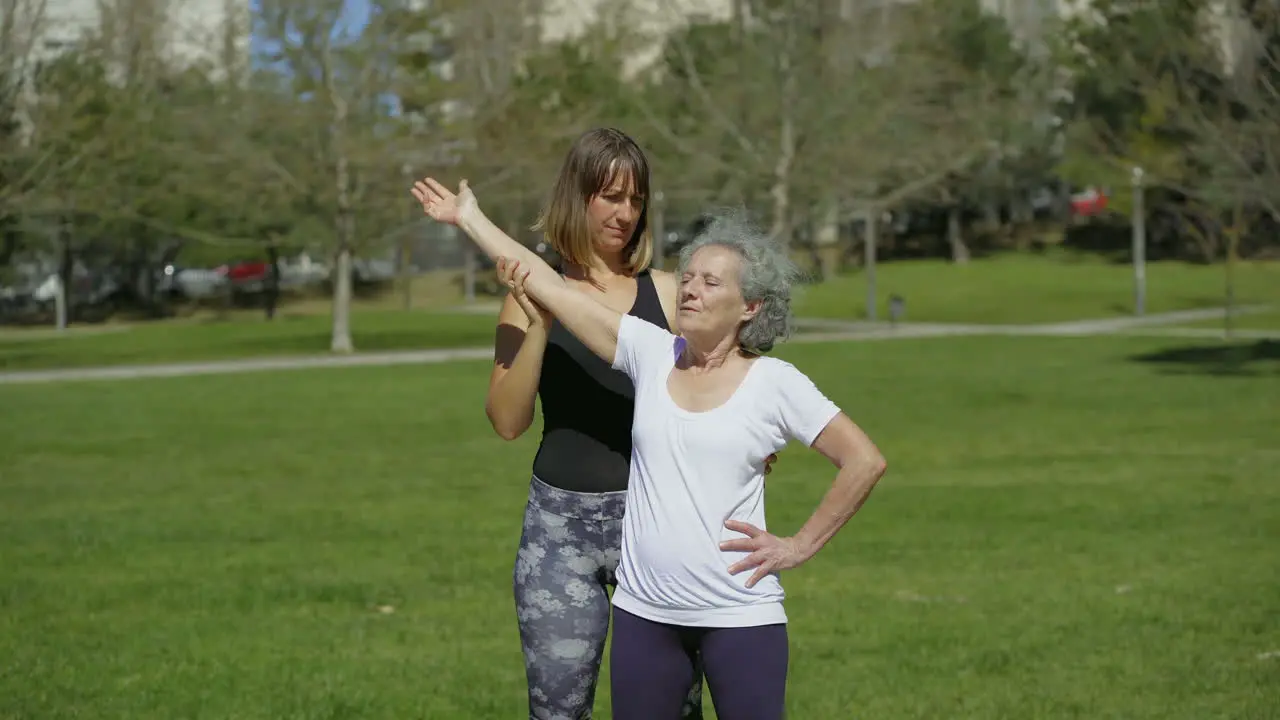 Smiling senior woman training with coach on green lawn