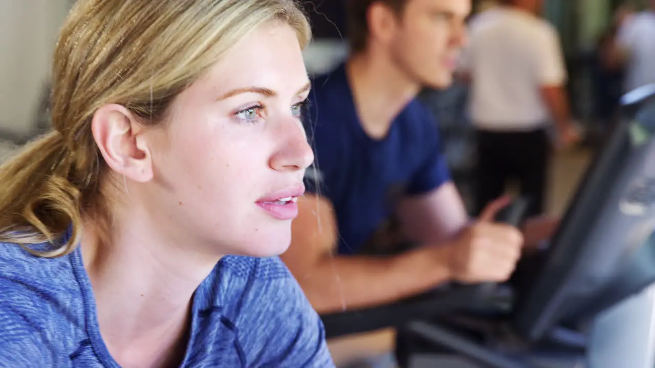 Close Up Of Woman Exercising On Cycling Machines In Gym