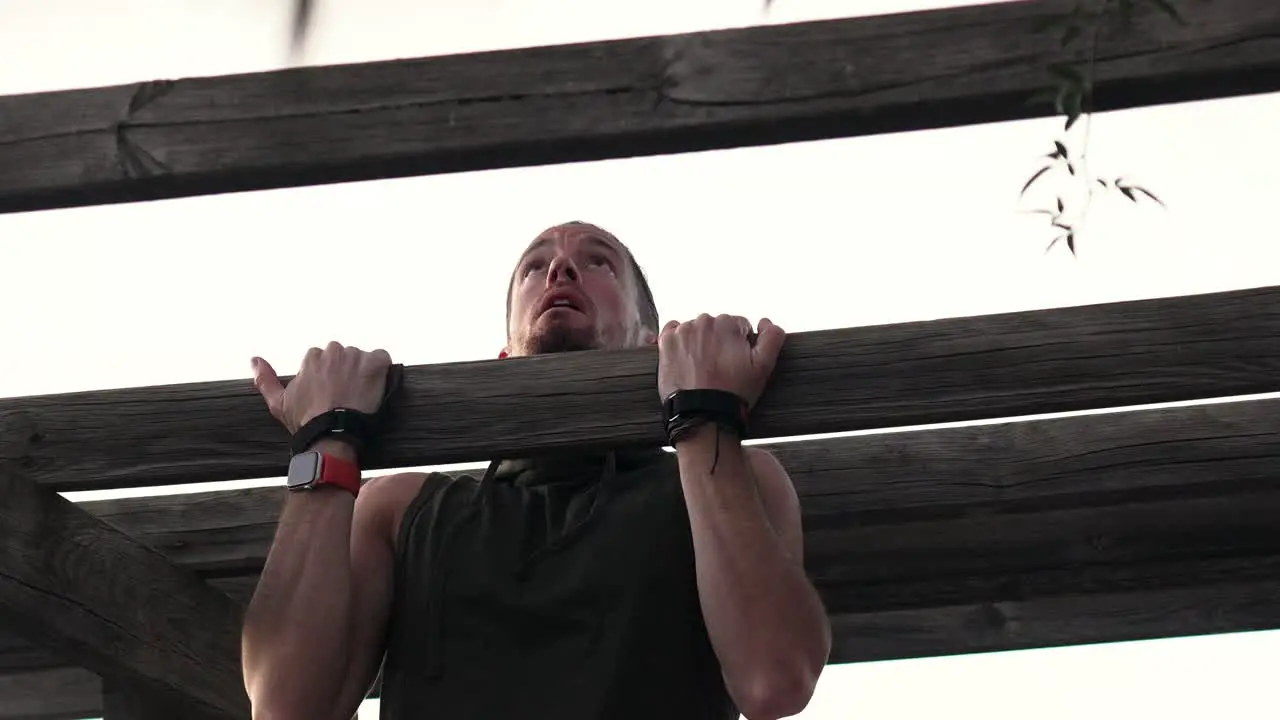 Sportsman doing push-ups on a wooden beam in a park