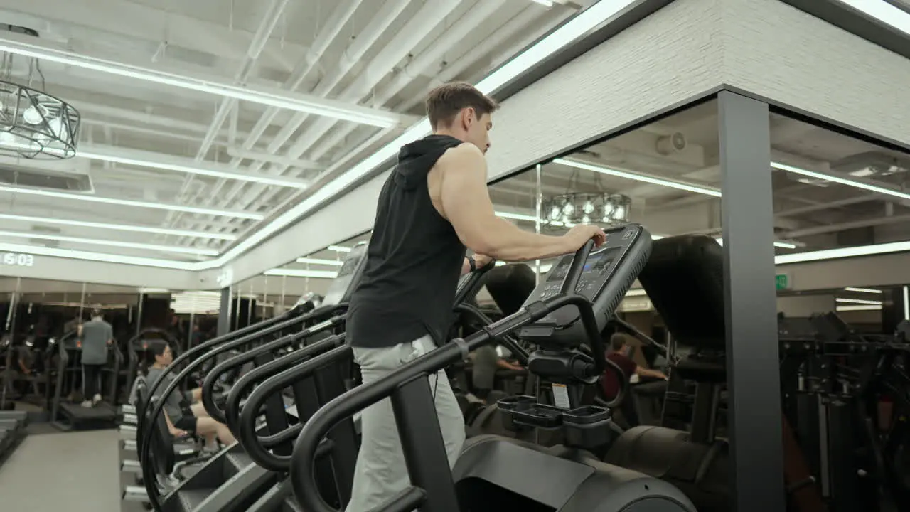 Mature Bearded Muscular Man Doing Cardio on Stair Climber Machine in Fitness Center low angle