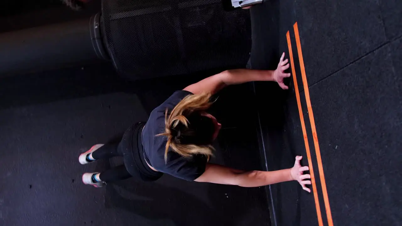 The athletic girl in the gym performs a handstand with her legs up in the air