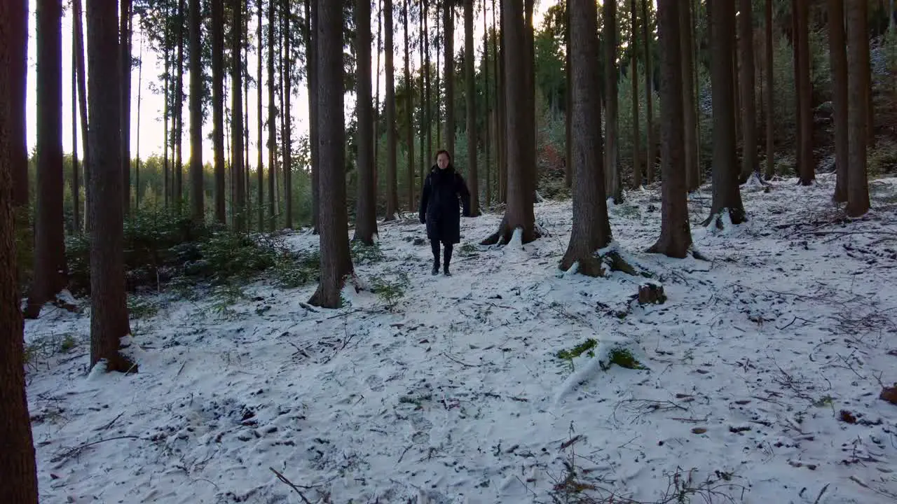 Man in winter clothes with a backpack walks through a snowy forest off the road