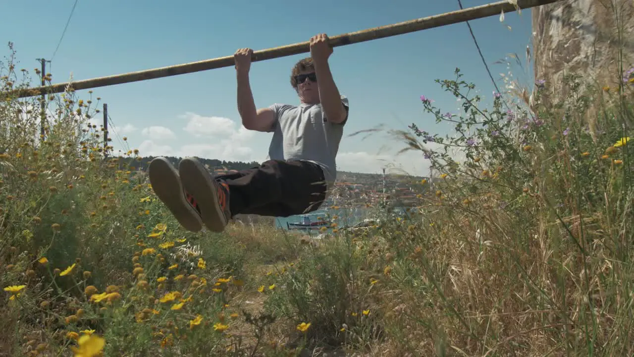 Young fit man does bicep curls street workout using bar