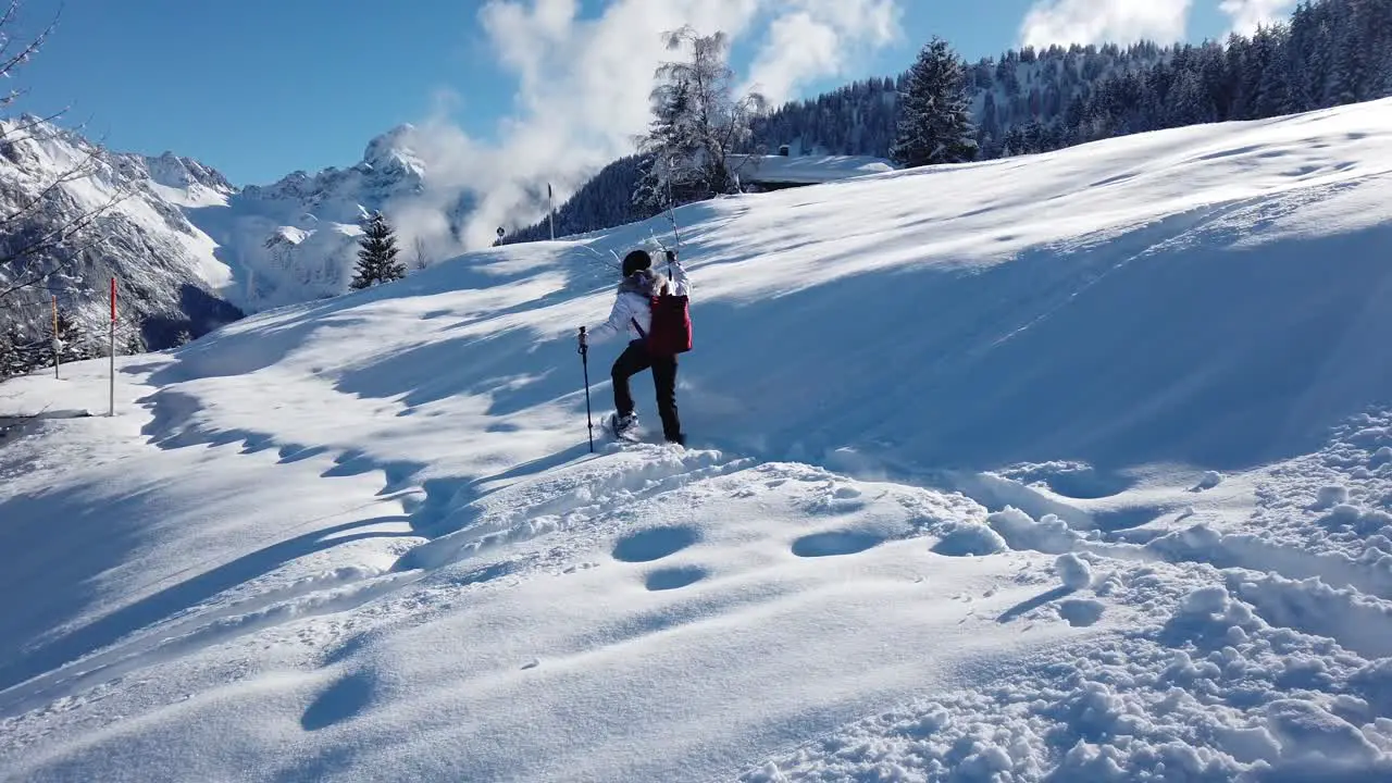 One woman walking on the snow with snow shoes and walking sticks