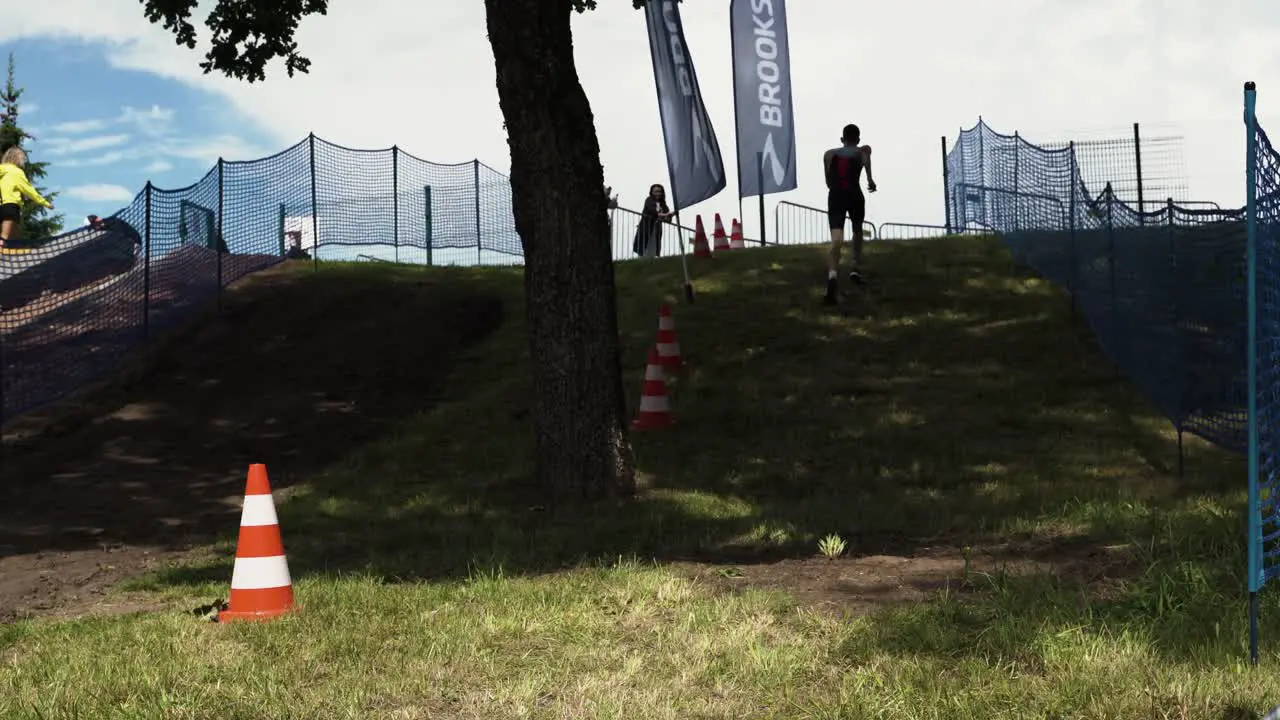 Tilt up along dirt running path during outdoor triathlon as man runs past