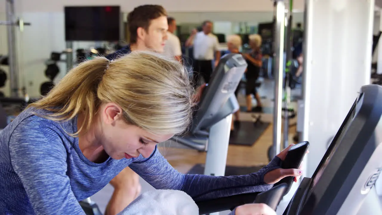 Woman Exercising On Cycling Machine In Gym