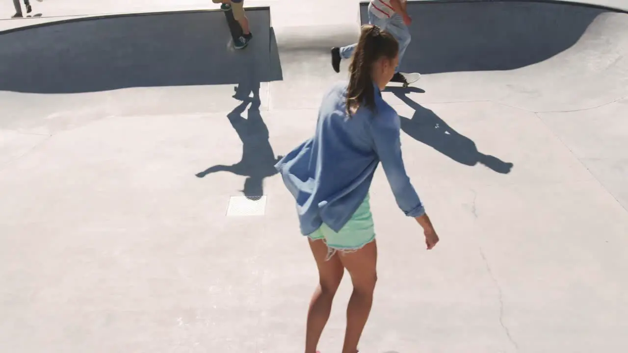 Caucasian woman and two male friends skateboarding on sunny day