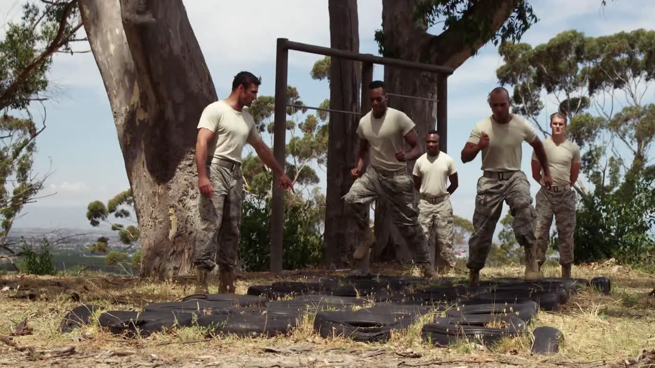 Military troops running over tyres during obstacle 4k