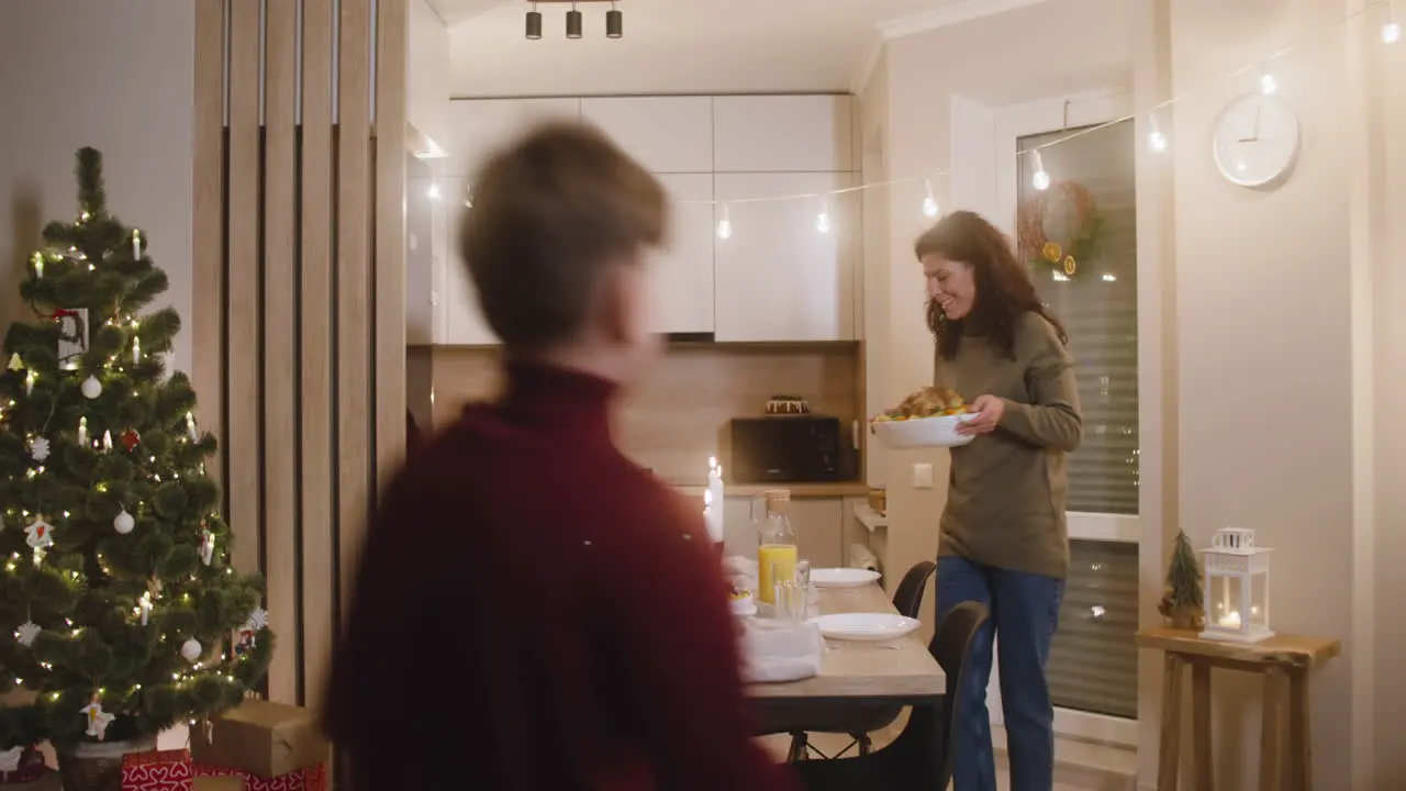 Mujer Morena Sacando Pavo Del Horno Hombre Pelirrojo Cierra El Horno Y Los Niños Vienen A La Mesa Y Toda La Familia Se Sienta Para La Cena Familiar De Navidad