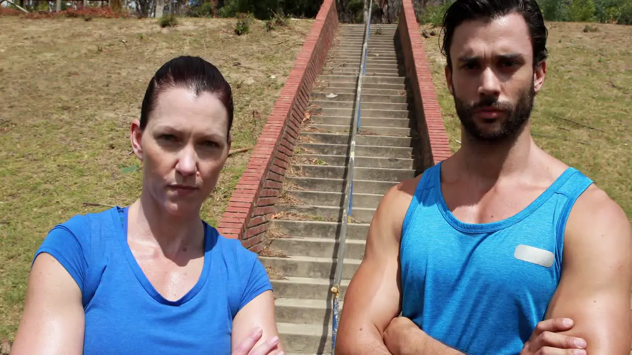 Portrait of fit man and woman standing with arms crossed