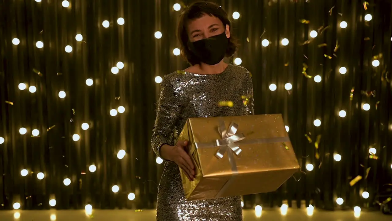 Junge Frau Mit Gesichtsmaske Und Abendkleid Die Eine Goldene Geschenkbox Und Fallendes Glitzerkonfetti Hält