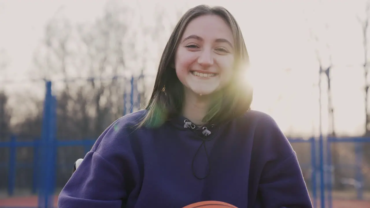 Glückliche Behinderte Frau Im Rollstuhl Die In Die Kamera Schaut Während Sie Einen Basketball Auf Dem Basketballplatz Hält