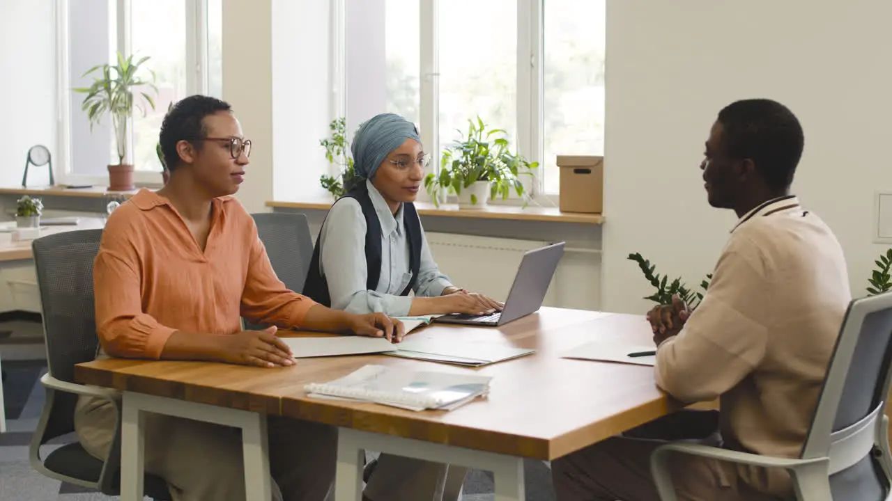 Eine Frau Und Eine Muslimische Mitarbeiterin Interviewen Einen Jungen Mann Der An Einem Tisch Im Büro Sitzt 5