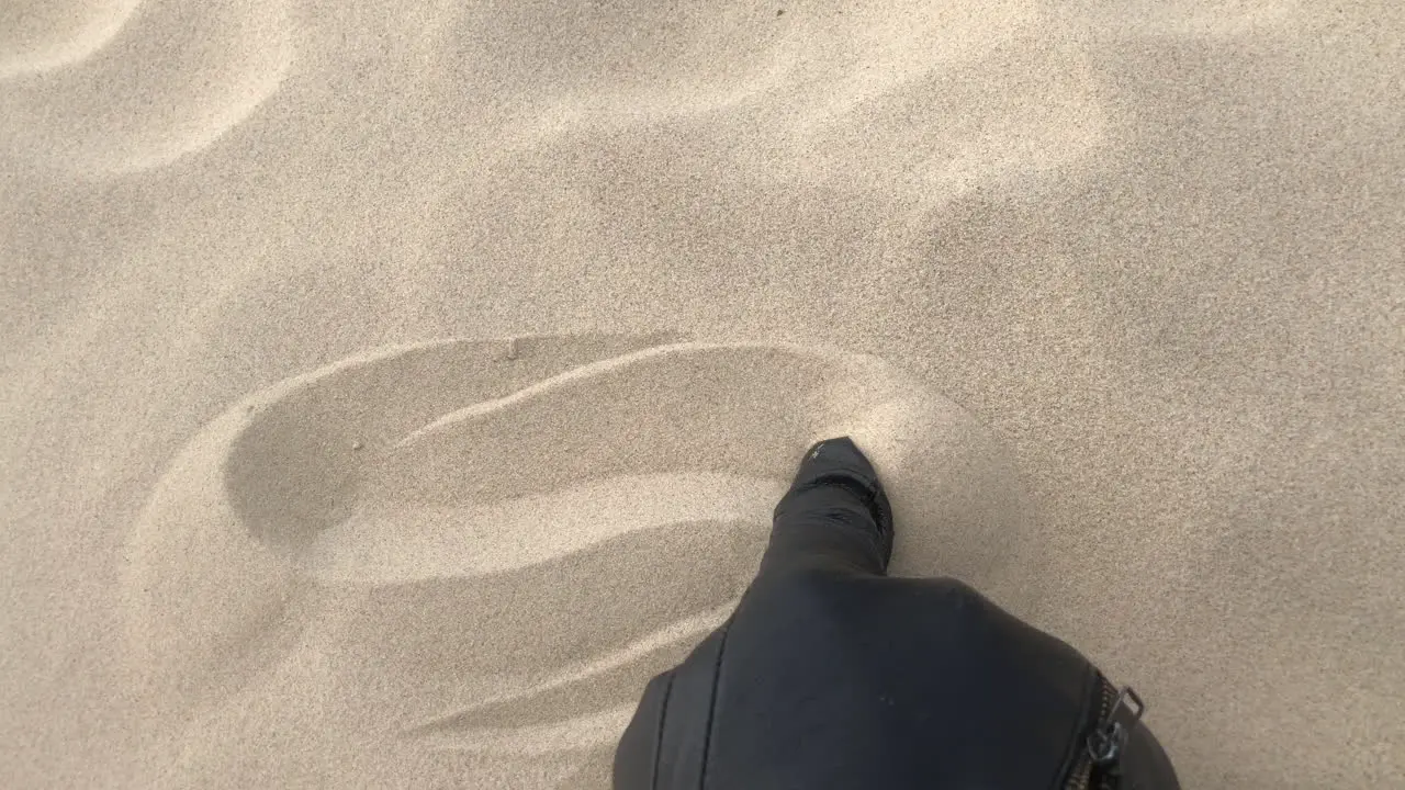 Shot of a black glove drawing waves in sand