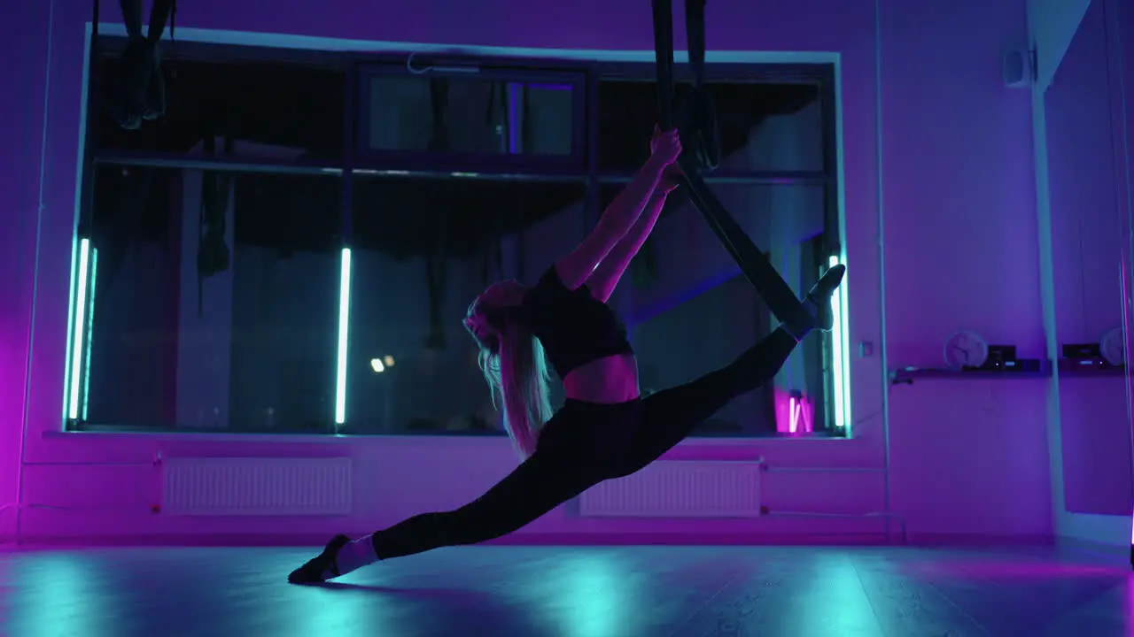 Eine Frau Macht Sportyoga In Der Luft Auf Einer Hängematte Im Neonlicht Und Führt Anmutige Übungen Und Bewegungen Aus Dehnübungen Und Tanzen In Zeitlupe Aus