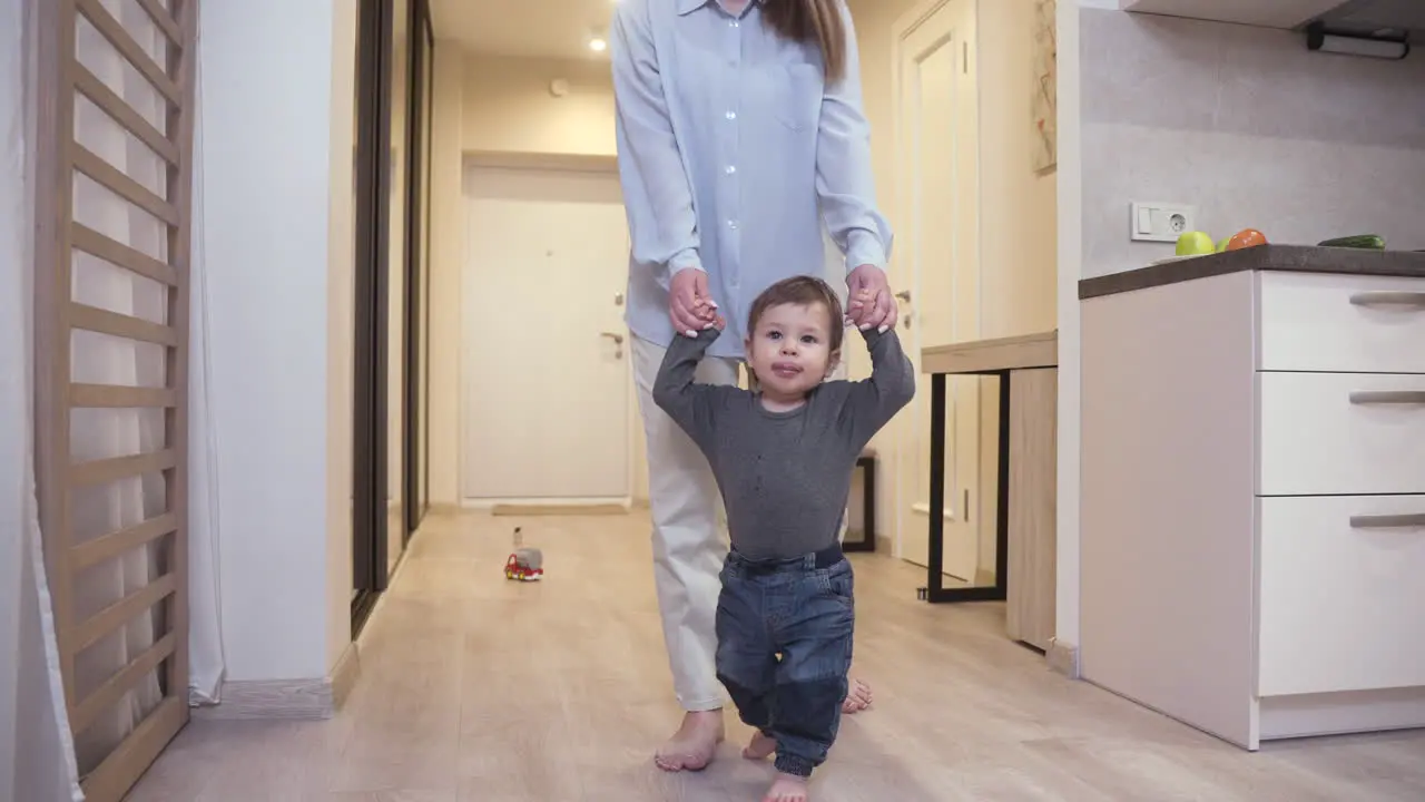 Mutter Hilft Ihrem Baby Bei Den Ersten Schritten Vom Flur Ins Wohnzimmer Zu Hause