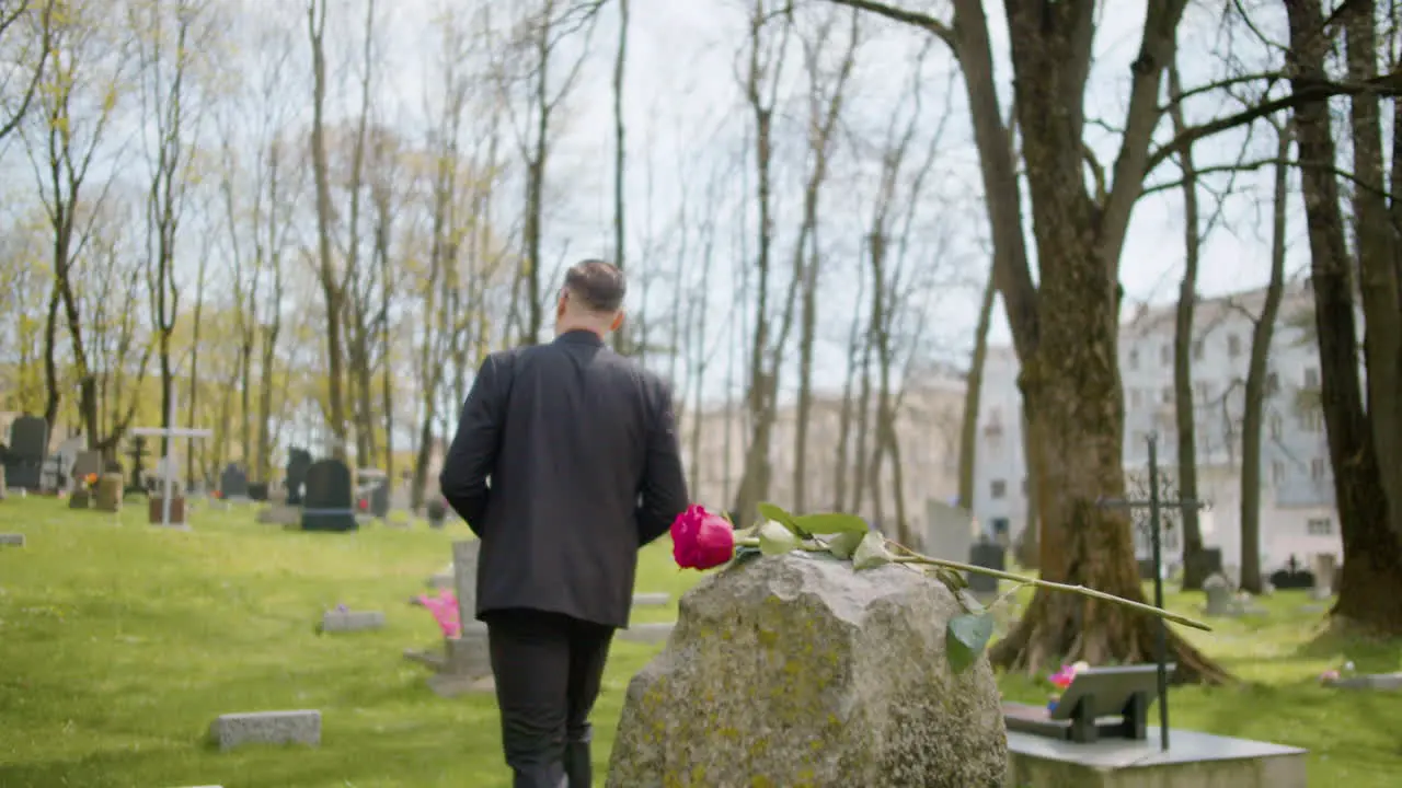 Mann Im Schwarzen Anzug Vor Einem Grabstein Mit Roter Rose