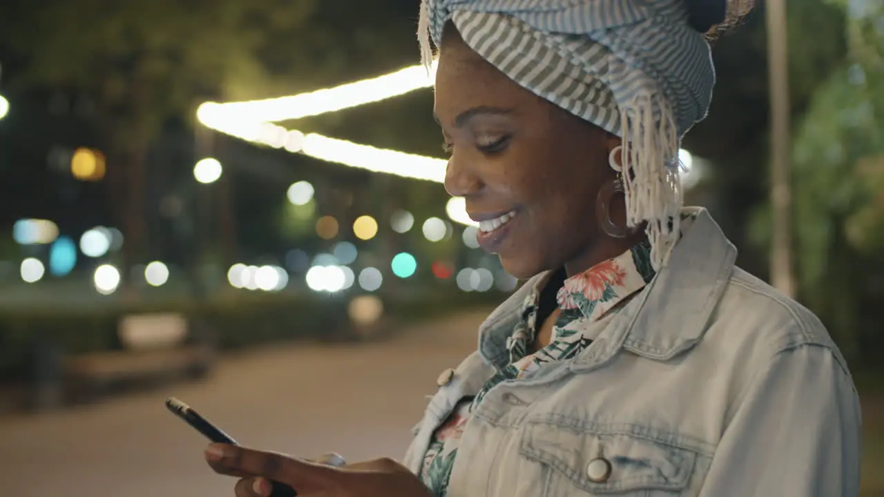 Mujer Afroamericana Sonriendo Y Enviando Mensajes De Texto Por Teléfono En El Parque Por La Noche