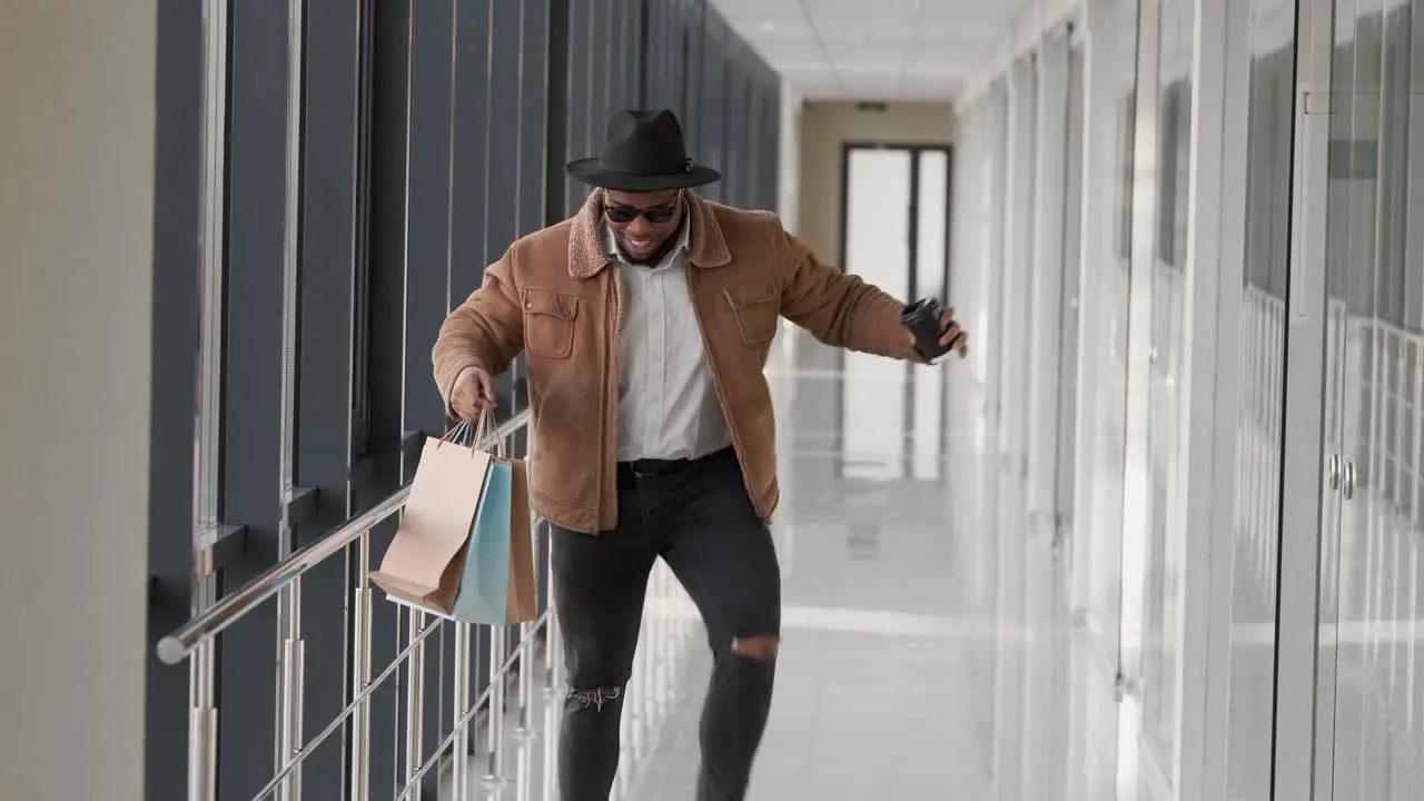 black stylish young man walking down the mall after shopping