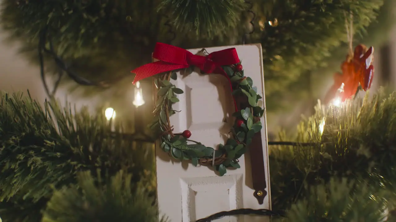 La Cámara Se Enfoca En La Puerta Blanca Decorada Con Una Corona De Navidad Colgando De Un árbol De Navidad Con Luces 1