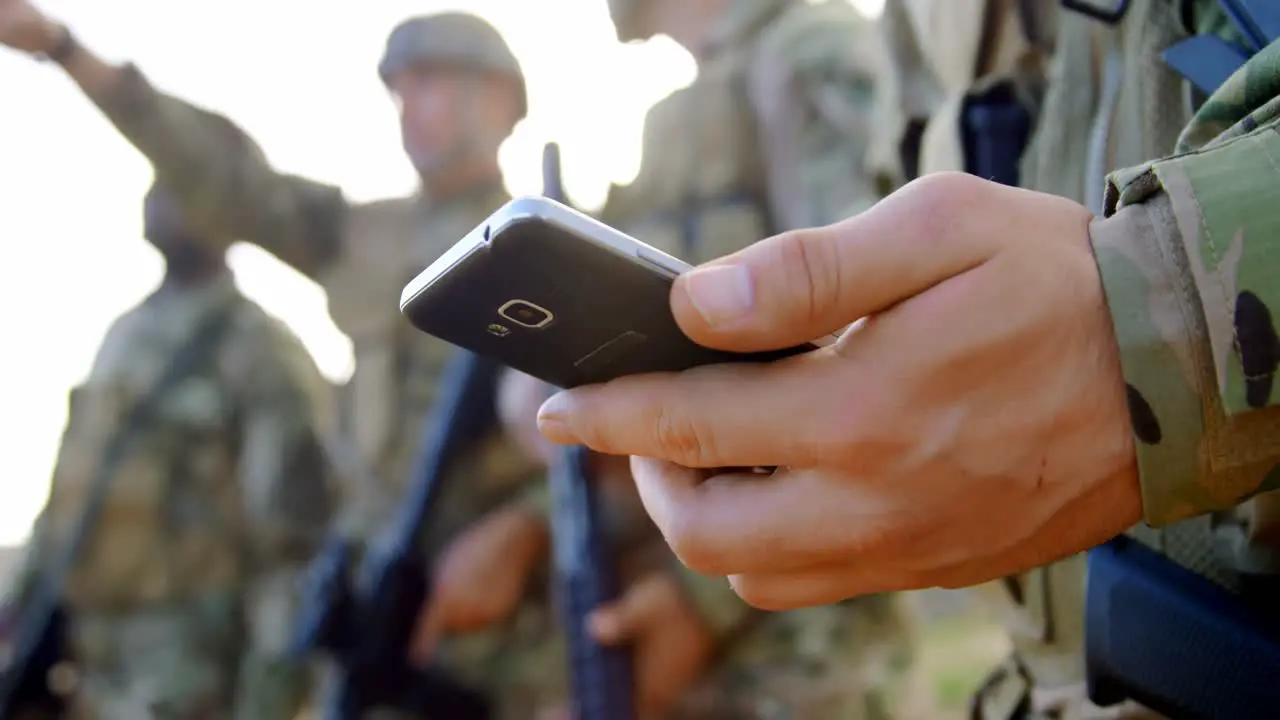 Mid section of caucasian military soldier using mobile phone during military training 4k