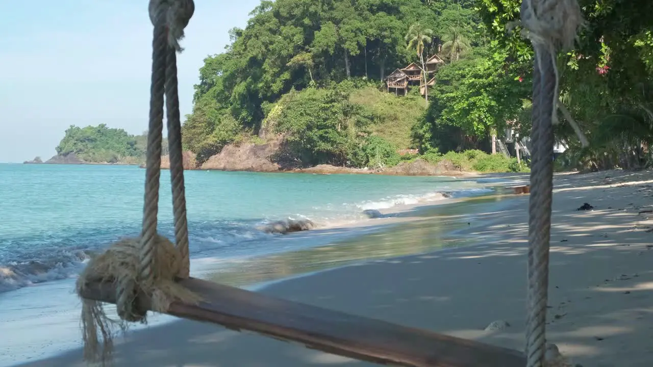 tropical beach in Thailand with rope swing and jungle coastline static shot with zoom