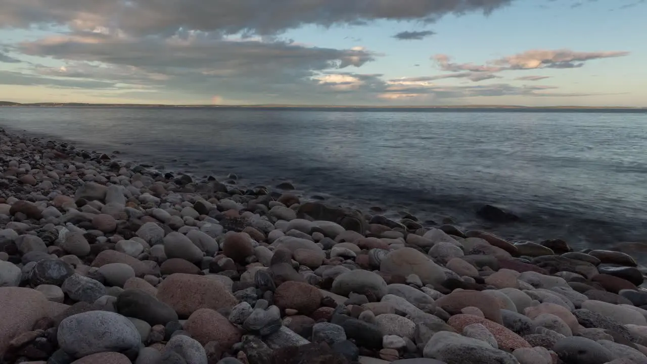 Time lapse footage of rocky beach at sunset and rainbow in a far