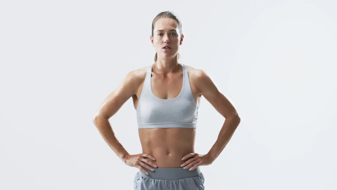 Fit young Caucasian woman athlete stands confidently on a white background with copy space