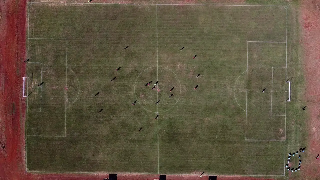 Drone static look down on football pitch ball passed between team players and other players train on the sidelines