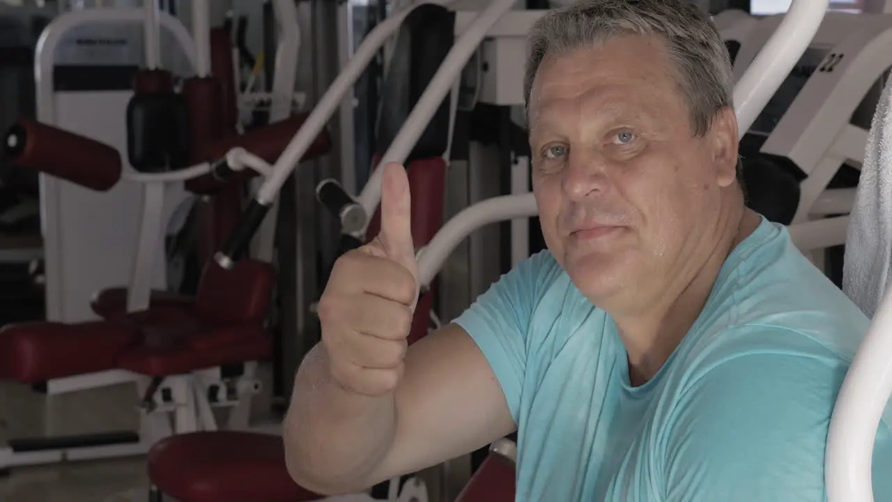 Senior man with thumb up and smile between exercises in gym