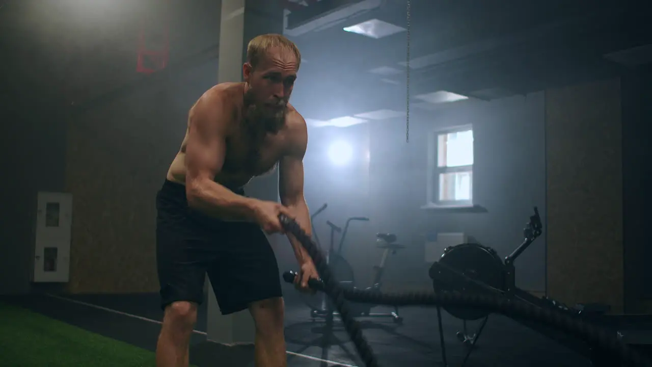 Male athlete working out with ropes in old building Athlete man in training with ropes near mirror Battle Rope