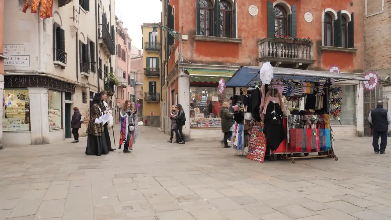 Street view in Venice after the cancelled Carnival Couple in venetian costumes near a street vendor