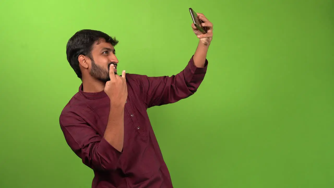 Handsome man taking selfy with smartphone isolated on green screen