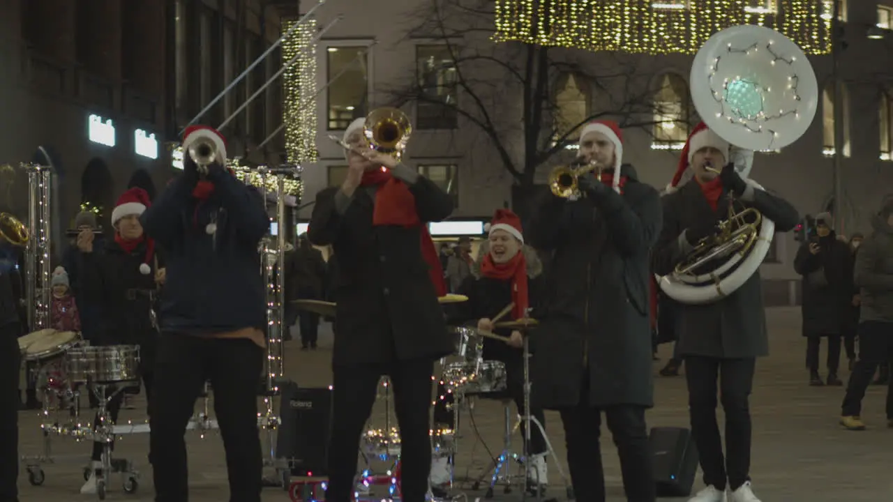 Street musicians dressed as Santa Claus play trumpets and drums