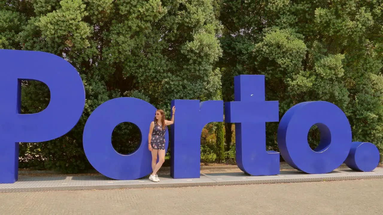 Tourist standing in front of a large sign establishing "Porto" in Portugal