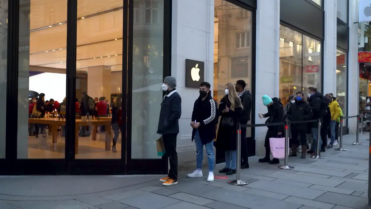 People wearing facemasks lining up in front of Apple Store in Winter