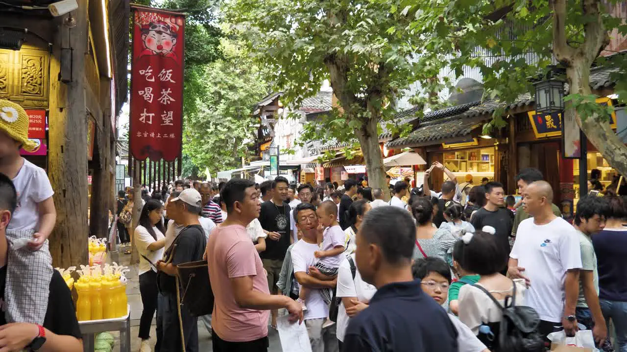 Daytime capture of crowd at pedestrian area of Chengdu's Kuanzhai Alley vibrant street vendors and artisan shops selling handicrafts and traditional trinkets add to the area's lively ambiance