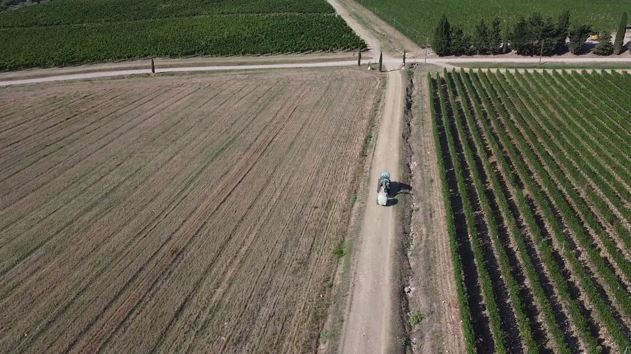 Agricultural tractor moving between neighboring wheat and vineyard fields in small town near Tuscany  Italy