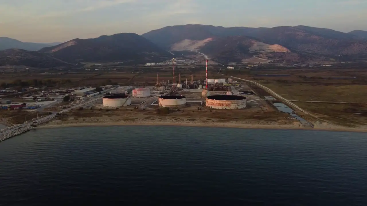 Aerial approach to oil refinery by the sea at dusk