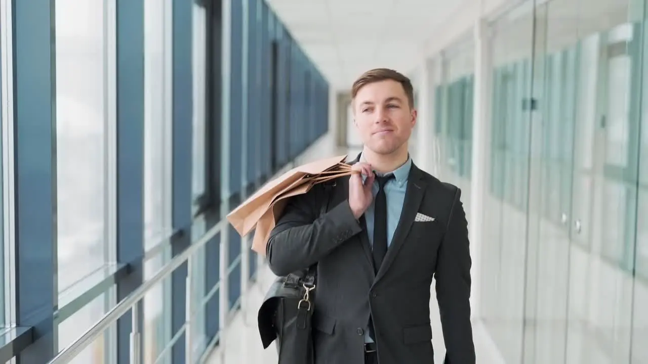 Pretty smiling man walks down the hall of shopping mall after shopping