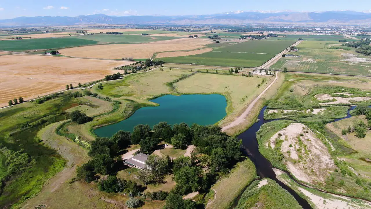 Drone video of a stunning green lake among pasturelands and bordered by trees