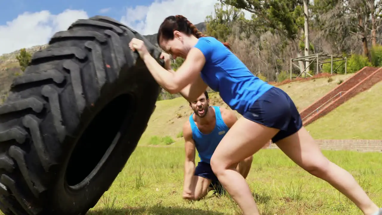 Male trainer giving training to woman during obstacle course