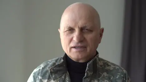 Headshot of aged Caucasian military man indoors Close-up portrait of frustrated depressed veteran in uniform Mental health problems and crisis concept