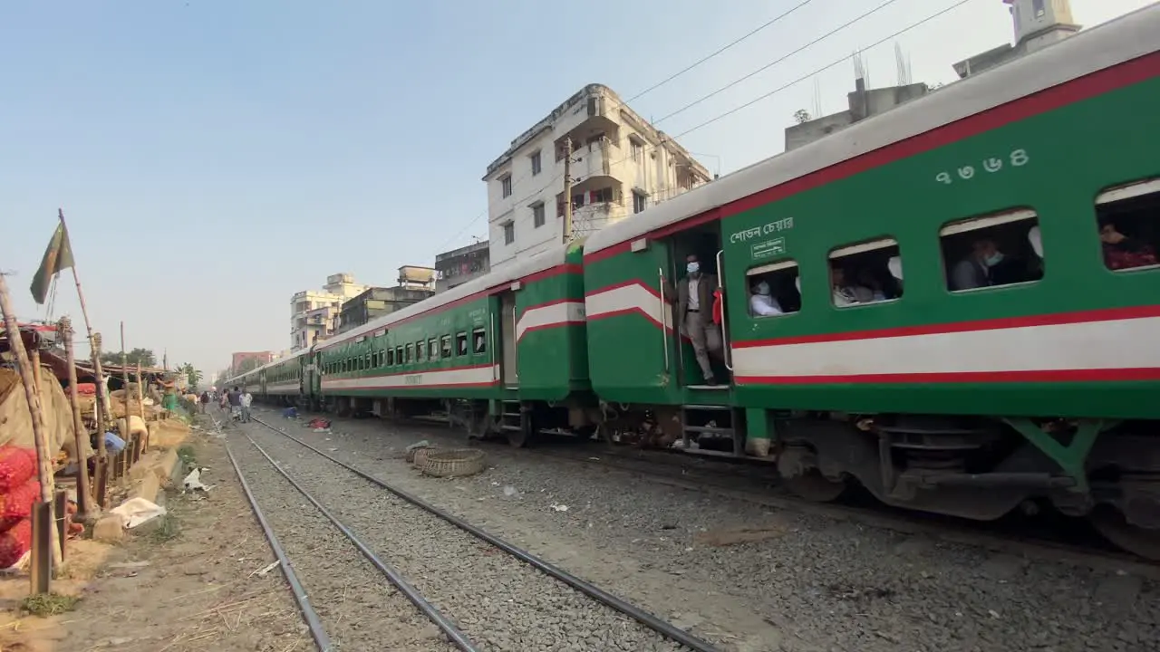 View of the coaches of a train passing through a city market with buildings on the side of the track in Dhaka Bangladesh